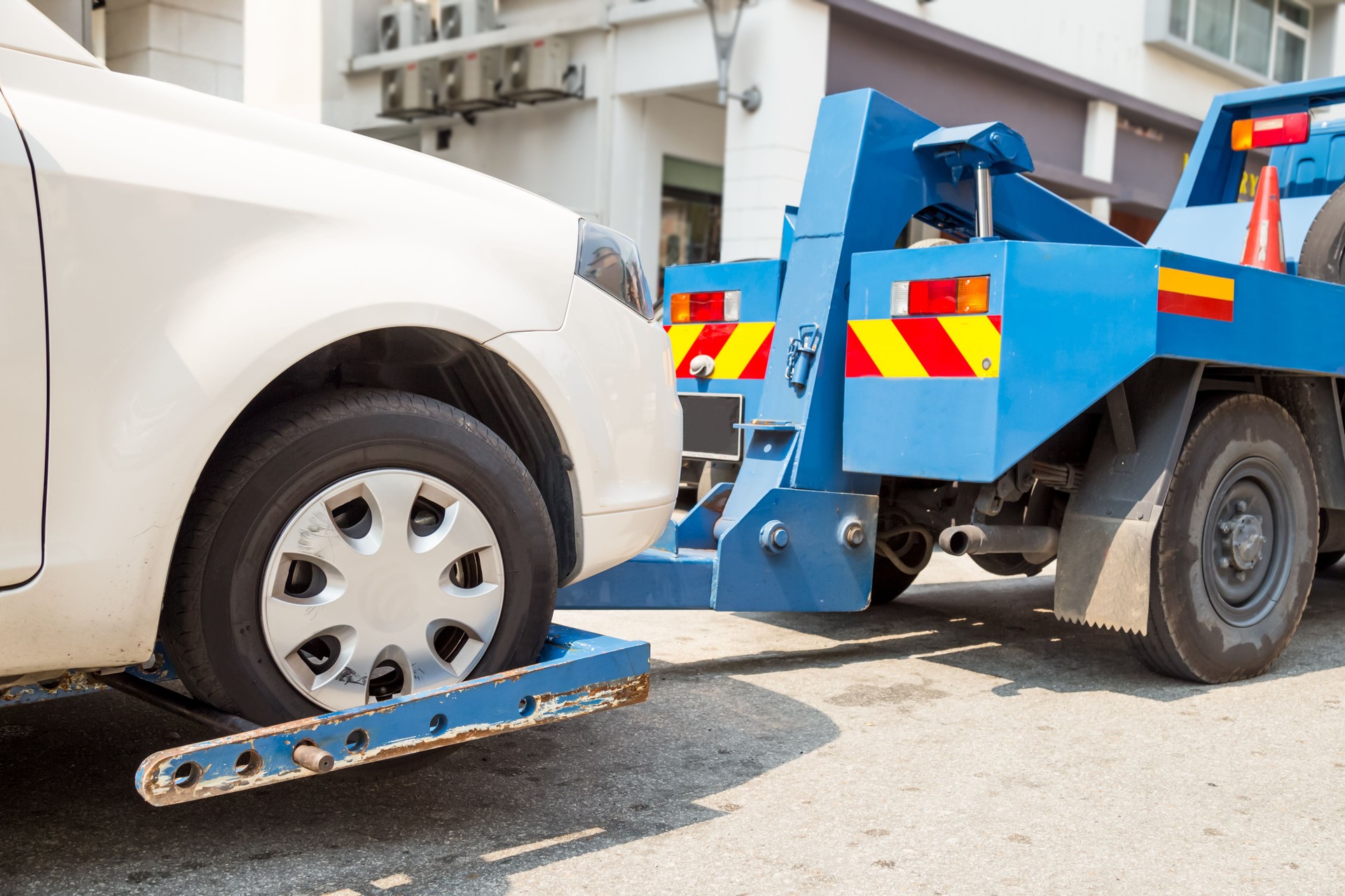 Tow truck towing a broken down car on the street